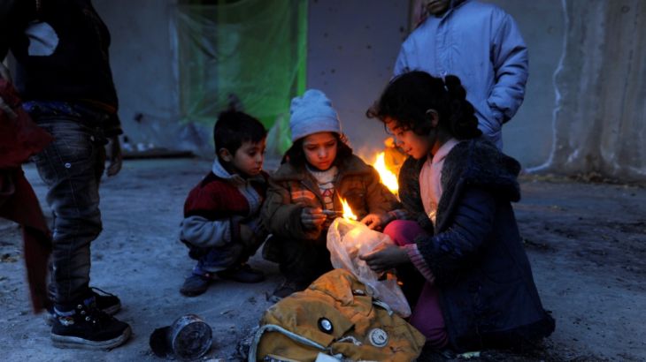 Syrians evacuated from eastern Aleppo, light a fire using plastic bags to keep warm, inside a shelter in government controlled Jibreen area in Aleppo