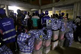 Polling agents stand next to ballot boxes at a collection center at the Odorkor police station in Accra, Ghana