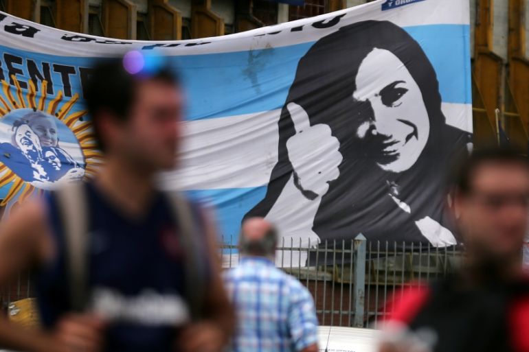 Supporters of former Argentine President Fernandez de Kirchner stand in front of a banner with her image as they wait for her to leave court in Buenos Aires