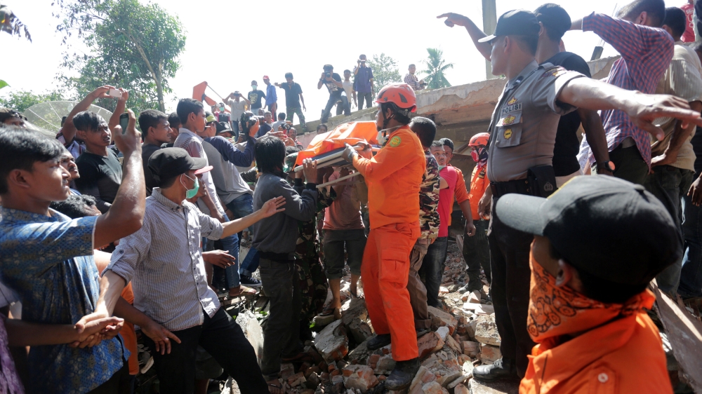 Rescue workers and police remove a victim from a collapsed building following an earthquake in Pidie Jaya [Irwansyah Putra/Reuters] 