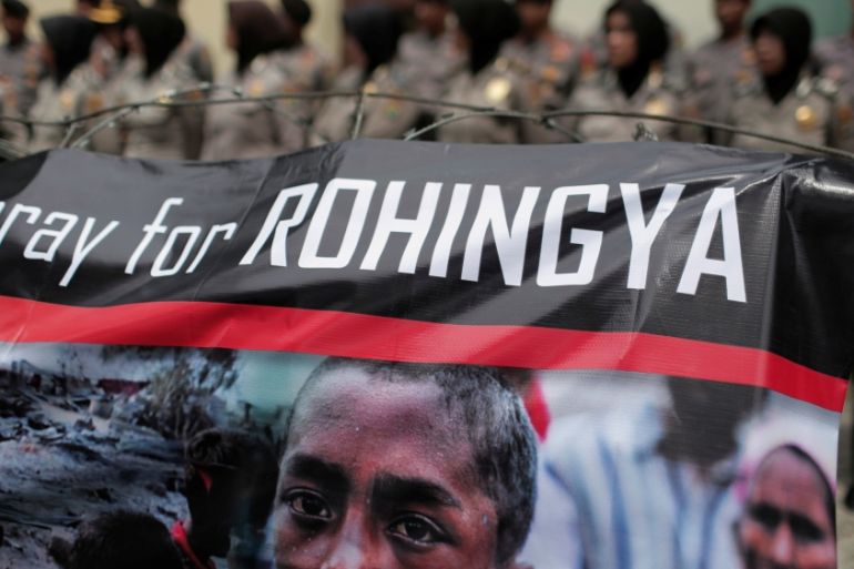 A banner is seen during a protest against what demonstrators say is the crackdown on ethnic Rohingya Muslims in Myanmar, as police stand guard in front of the Myanmar embassy in Jakarta
