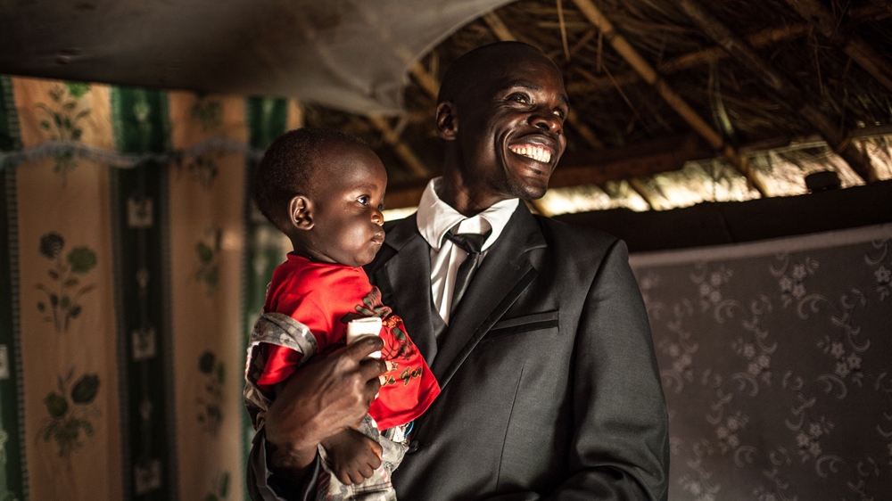 'Before, I was not free. It's so much better to work for myself and earn an income instead of just receiving charity,' says Simon Peter Otoyo, pictured with his son [Aurelie Marrier d'Unienville/Sightsavers/Al Jazeera] 