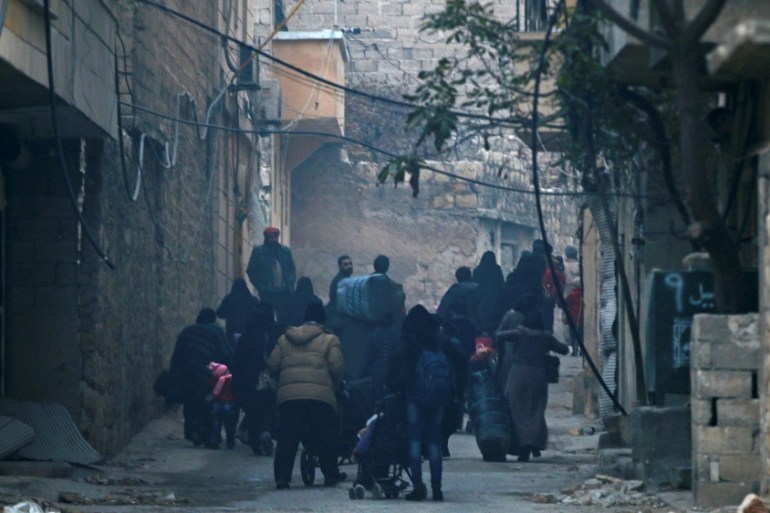 People carry belongings as they flee deeper into the remaining rebel-held areas of Aleppo