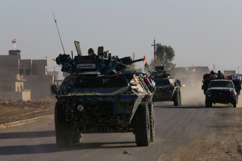Iraqi security forces members drive military vehicle in Qaraqosh, near Mosul