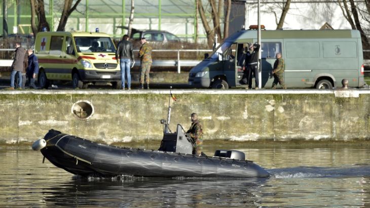 A Belgian army soldier in a boat searches the Meuse river for a teenager that was carried away on Sunday by the flooded river, in Tihange