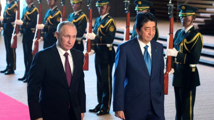 Russian President Vladimir Putin and Japanese Prime Minister Shinzo Abe review the guard of honour during a meeting in Tokyo