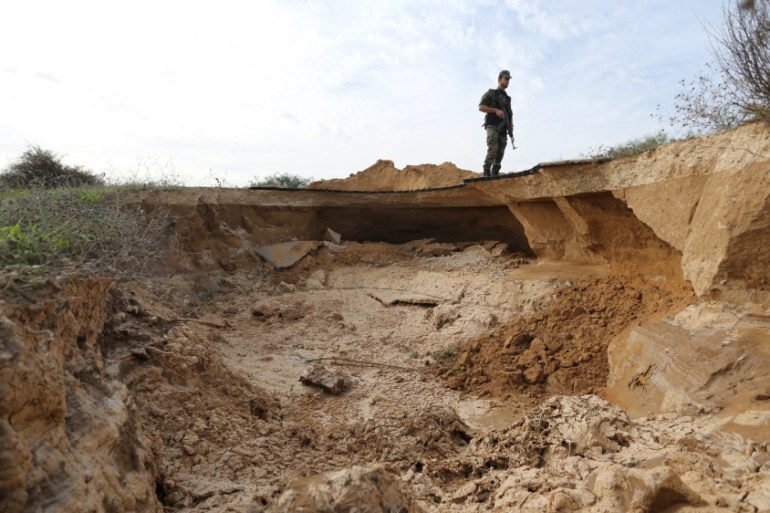 Member of Palestinian security forces loyal to Hamas stands guard as he views a landslide caused by floodwater pumped by Egyptian forces to destroy a network of Palestinian tunnels, near the border be
