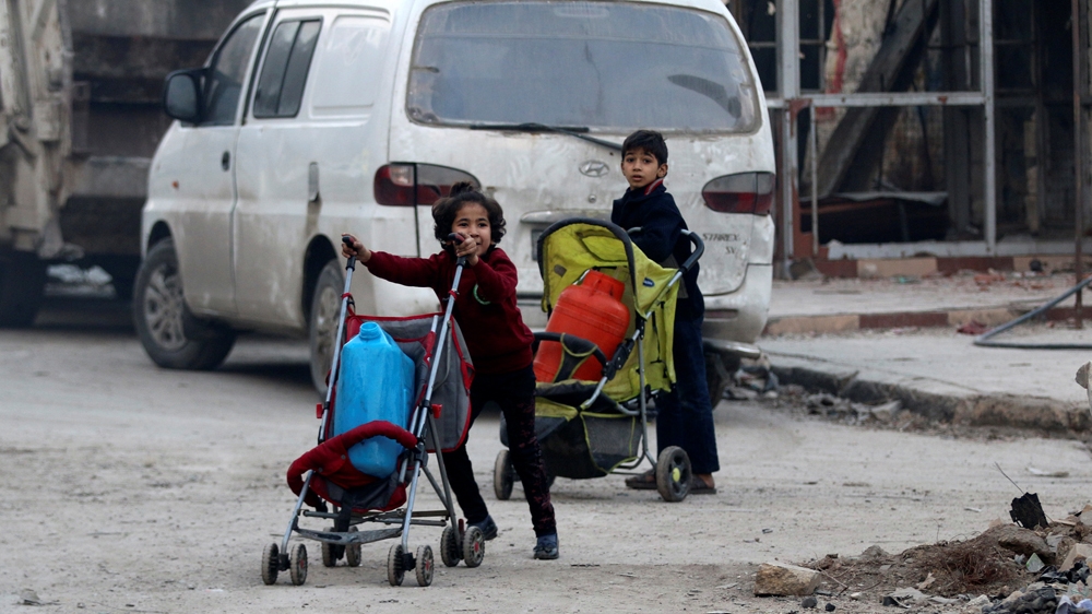 Children push containers in strollers as they flee deeper into the remaining rebel-held areas of Aleppo [Abdalrhman Ismail/Reuters]
