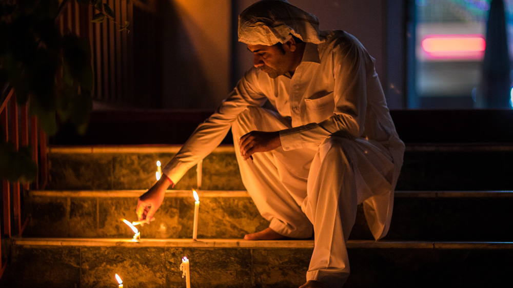 A Hindu man lights a candle on the steps in front of Asyamee, a Hindu temple in Kabul [Ivan Flores/Al Jazeera] 
