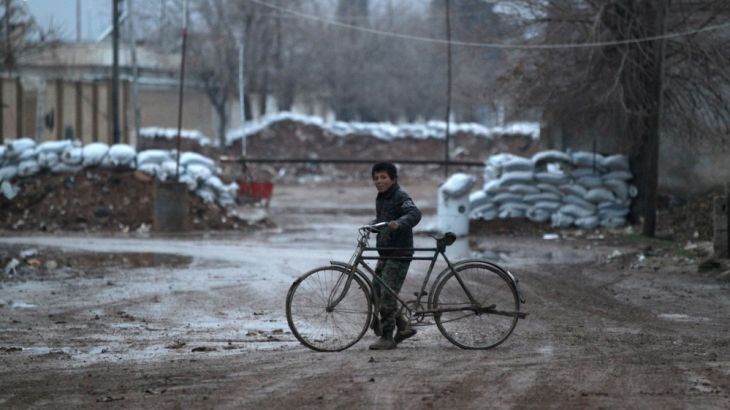 A boy walks his bike near stacked sandbags in al-Rai town, northern Aleppo province