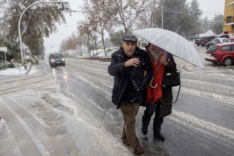 A couple walks through the surprising snow on Nino de Mula in Murcia, eastern Spain