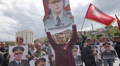 Kosovar Albanians wave flags and hold portraits of Sulejman Selimi, commander of the KLA who was sentenced to 14 years in prison for war crimes, during a protest in front of the parliament building in Pristina, Kosovo, in May 2015 [VALDRIN XHEMAJ/EPA]