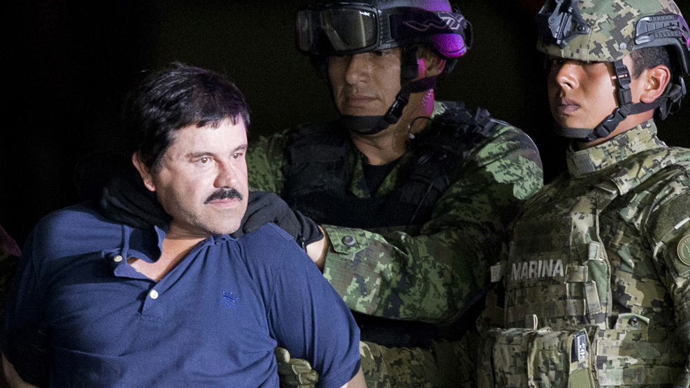 A handcuffed Joaquin 'El Chapo' Guzman is presented to the press as he is escorted to a helicopter by Mexican soldiers and marines at a federal hangar in Mexico City [File: Eduardo Verdugo/AP Photo] 