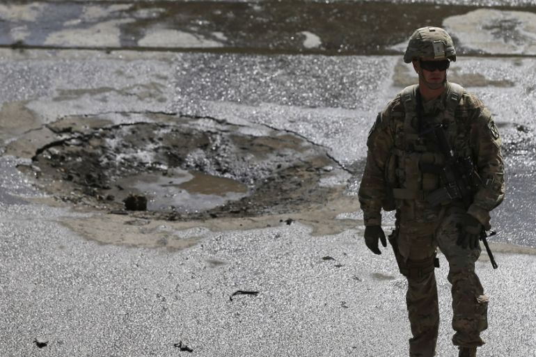 A NATO soldier stands at the site of a suicide car bomb blast in Kabul