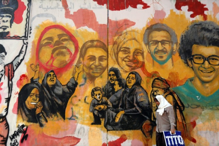 A woman walks past a graffiti near Tahrir Square in downtown Cairo