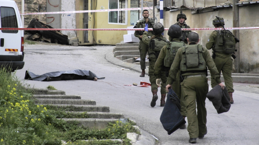 Israeli soldiers stand near the body Abed al-Fattah al-Sharif, who was shot while laying wounded on the ground after a stabbing attack in Hebron in March 2016 [The Associated Press]