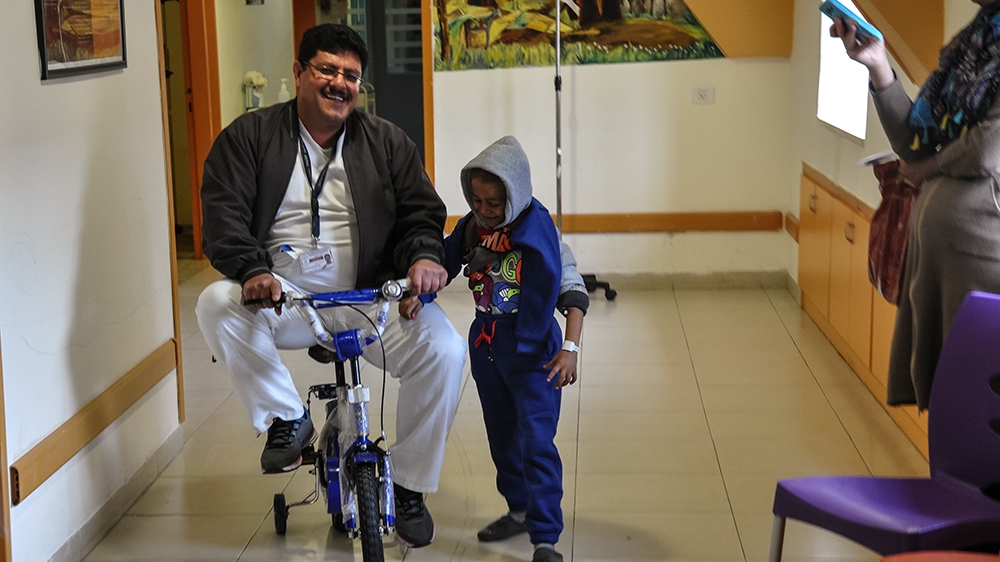 'The presence of the school today has elevated the spirit and mood of the students,' says Mohamad Qabaja, seen playing with Amjad in the hospital's corridors [Zena al-Tahhan]