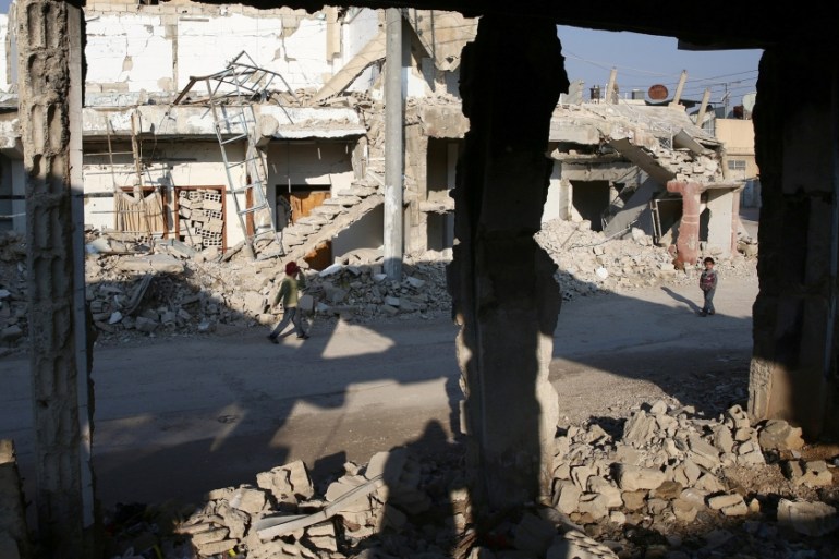Children walk near damaged buildings in the rebel held besieged city of Douma