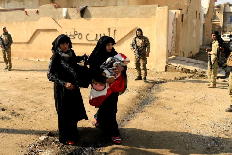 A displaced Iraqi woman, who fled the Islamic State stronghold of Mosul, carries her baby in the Mithaq district
