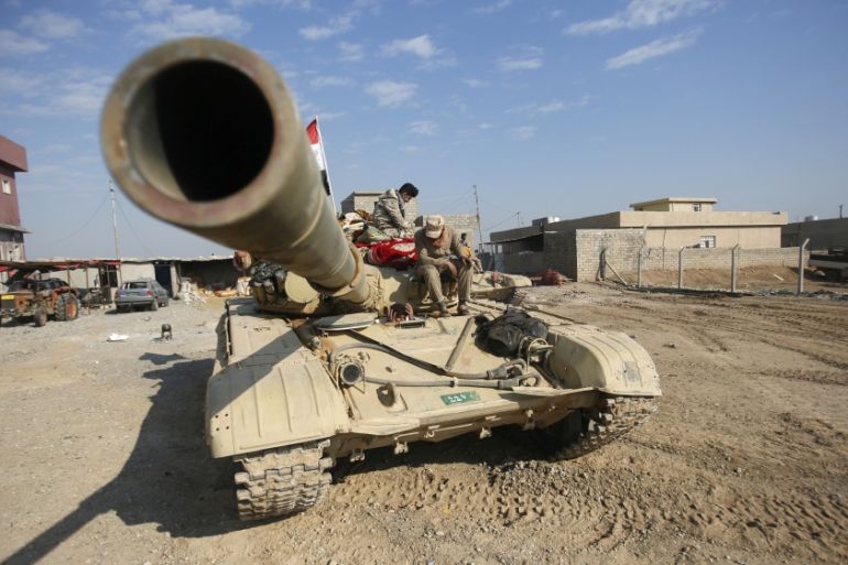 Iraqi army members sit on a tank during a battle with Islamic State militants in Talkeef district, north of Mosul