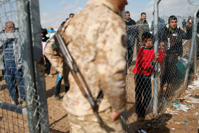Displaced Iraqi people who fled from fighting Islamic State militants in Mosul, stand behind the fence at Khazer camp