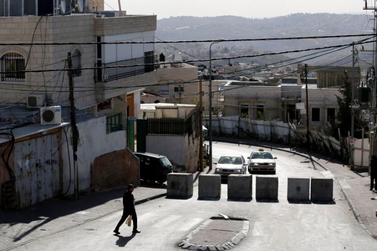 A man walks next to a newly erected concrete barriers at the entrance to Jabel Mukaber, the morning after a Palestinian rammed his truck into a group of Israeli soldiers,