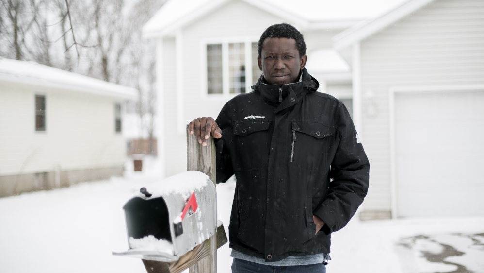 Musa Saidykhan, the former newspaper editor in The Gambia, stands in front of his home in Grand Rapids, Michigan, where he has lived since 2008. He was imprisoned and tortured in his homeland and fled across the border to Senegal in 2006 [Bryan Bosch/Al Jazeera]