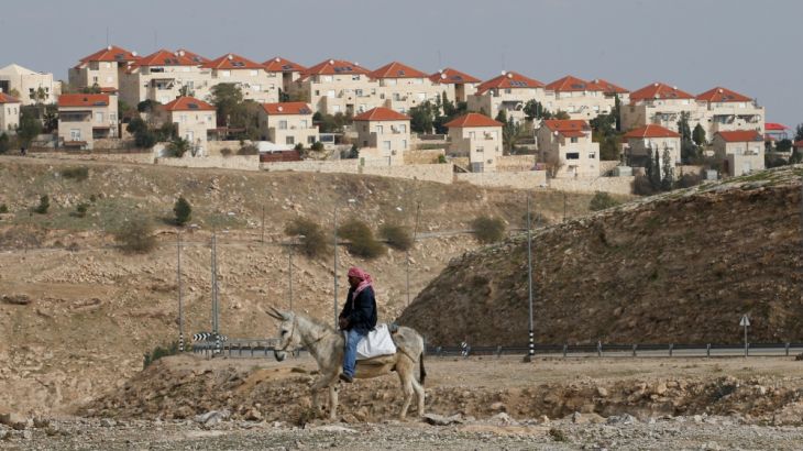 FILE PHOTO: A Palestinian man rides a donkey near the Israeli settlement of Maale Edumim, in the occupied West Bank