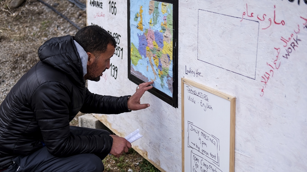 An asylum seeker looks at a map of Europe pinned to a board at one of the makeshift camps on the Greek island of Lesbos, November 2015 [Fahrinisa Oswald/Al Jazeera]