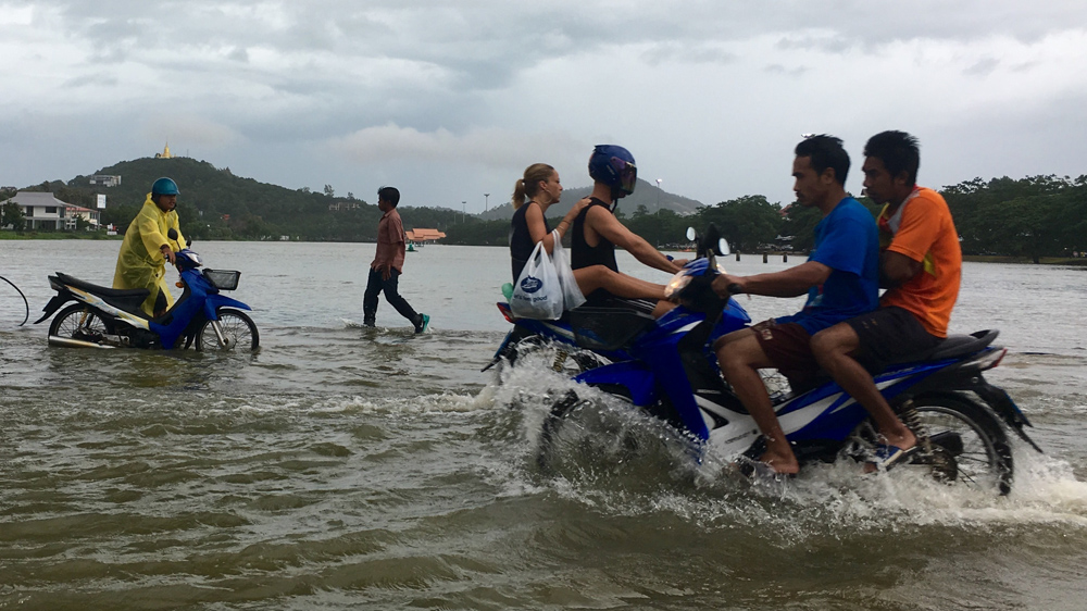 Tourists and locals use a road flooded on the island of Samui [Adam Schreck/AP]