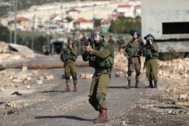 Israeli soldier aims his weapon towards Palestinian protesters during clashes following a protest against the near-by Jewish settlement of Qadomem, in the West Bank village of Kofr Qadom near Nablus