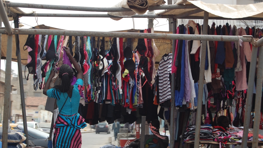 A woman sells clothes at the weekly market of Gueule Tapee in Dakar [Ndela Faye/Al Jazeera]