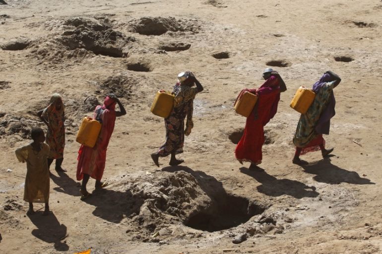 Women carry jerry cans of water from shallow wells dug from the sand along the Shabelle River bed, which is dry due to drought in Somalia''s Shabelle region