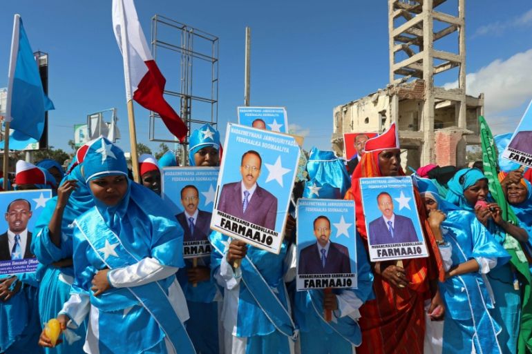 Women carry posters of the newly elected Somalian President Mohamed Abdullahi Mohamed as they celebrate his victory, near the Daljirka Dahson monument in Mogadishu