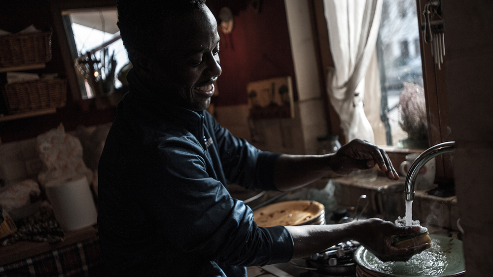 Saeed Mohammed helps out in the kitchen. At the Calo house everyone participates in house chores. [Mattia Cacciatori /Al Jazeera]