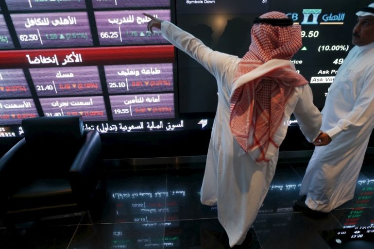 File photo of investors talking as they monitor screens displaying stock information at the Saudi Stock Exchange (Tadawul) in Riyadh