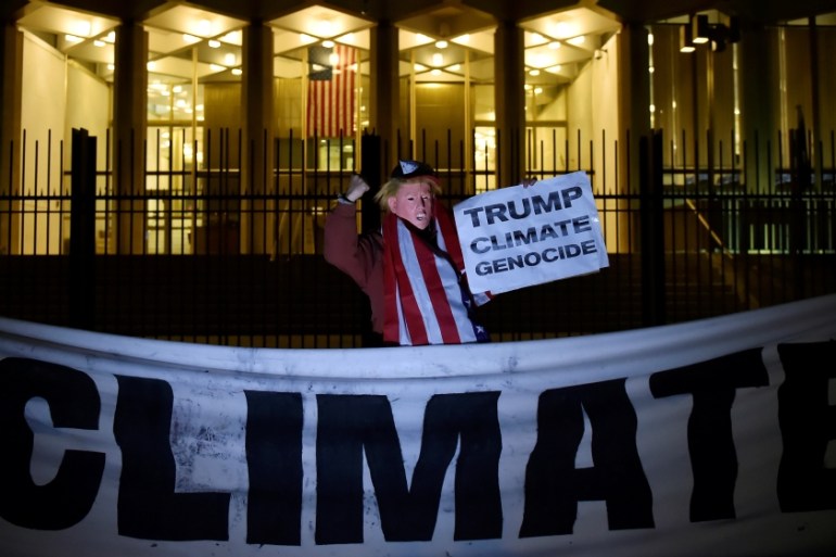 A man wearing a mask depicting U.S. President-Elect Donald Trump protests during a demonstration against climate change outside of the U.S. Embassy in London