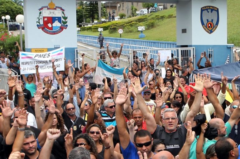 Members of the civil police and relatives of military police raise their arms in support of the police strike in front of a military police headquarters in Vitoria