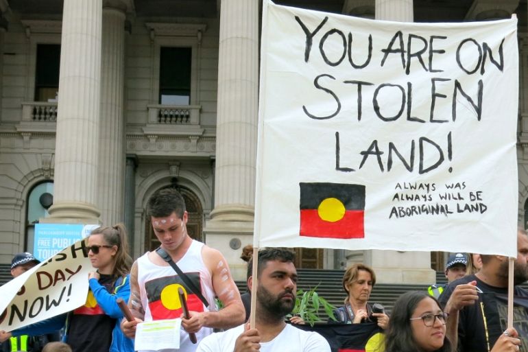 Aboriginal protesters hold signs as they demonstrate outside the Victorian State Parliament on Australia Day in Melbourne, Australia