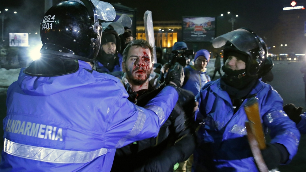 A wounded young man is arrested by the riot police [EPA]