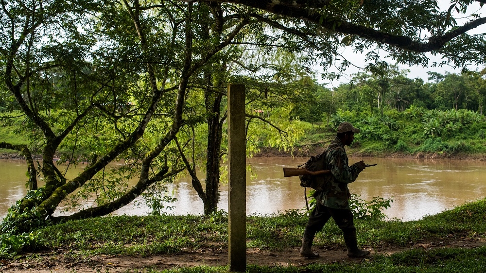 An armed Miskito patrols the banks of the Coco River. Settlers have occupied Miskito-owned farms, preventing the community from accessing its agricultural resources. [Alex McDougall/Al Jazeera]