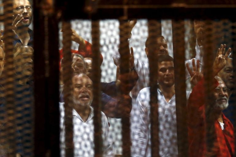 Muslim Brotherhood members wave with the Rabaa sign, symbolizing support for the Muslim Brotherhood, with other brotherhood members at a court in the outskirts of Cairo, Egypt