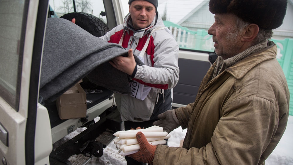 Leonid Tarasov, a pensioner in Old Avdiivka, on the edge of town closest to the frontline, receives blankets and candles from the International Committee of the Red Cross [John Wendle/Al Jazeera] 