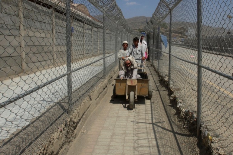 Men coming from Afghanistan move down a corridor between security fences at the border post in Torkham, Pakistan