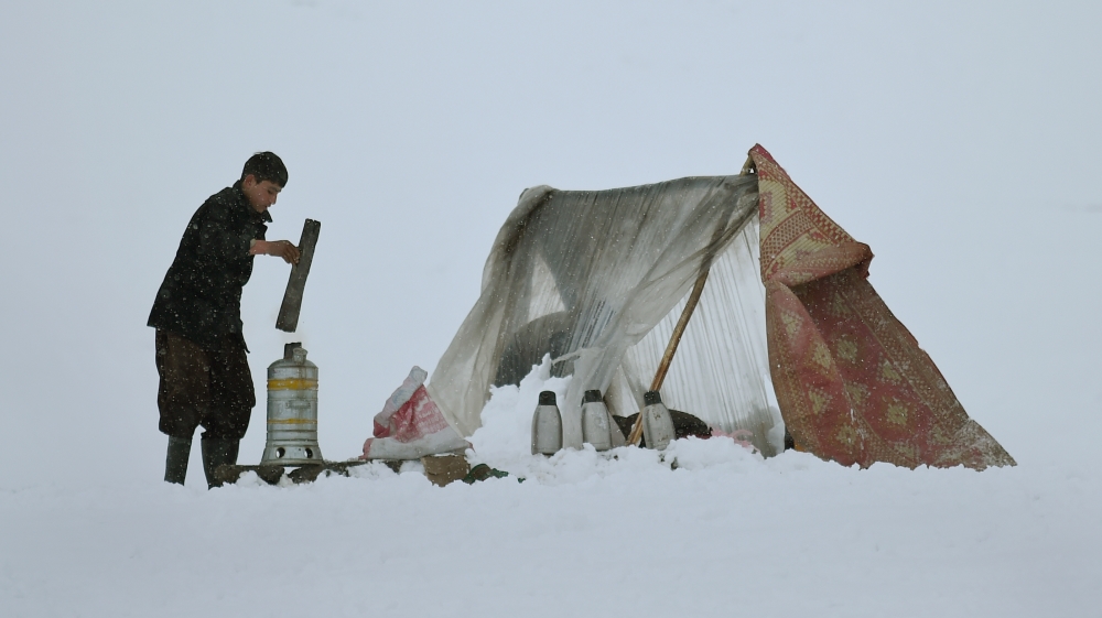 Afghan tea vendor Imran, 15, prepares tea for customers on a hillside during snowfall near Qargha Lake on the outskirts of Kabul [AFP]