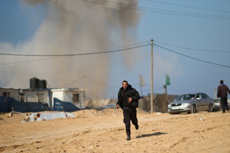 Palestinian security officer runs as smoke rises following what police said was an Israeli air strike on a Hamas post, in the northern Gaza Strip