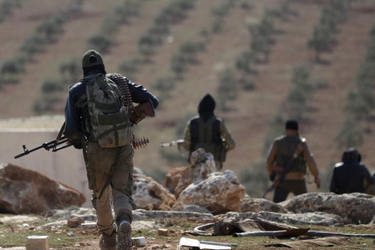 Rebel fighters carry their weapons as they walk on the outskirts of the northern Syrian town of al-Bab