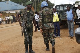 A peacekeeper serving in the MONUSCO and a Congolese soldier stand guard as residents gather following recent demonstrations in Beni in North Kivu province