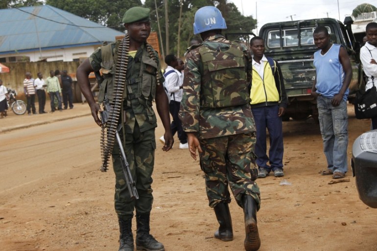 A peacekeeper serving in the MONUSCO and a Congolese soldier stand guard as residents gather following recent demonstrations in Beni in North Kivu province