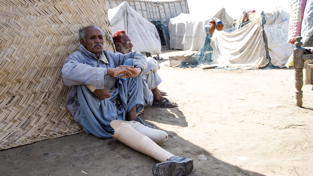 Jumun, left, who lost his right leg in an accident, and Ramzan, right, are the only two adult men of their family left in the village [Faras Ghani/Al Jazeera]
